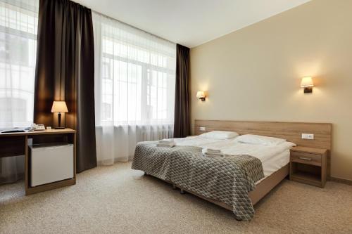a bedroom with a bed and a desk and window at Old Town Trio in Vilnius