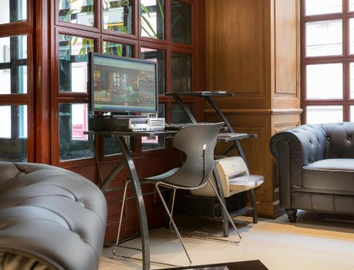 a room with a desk with a computer and chairs at Hotel Lautrec Opera in Paris