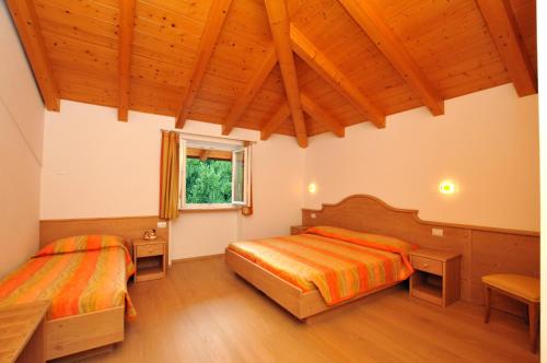 TassulloにあるAgritur Le Pergoletteの木製の天井の部屋にベッドが2つある