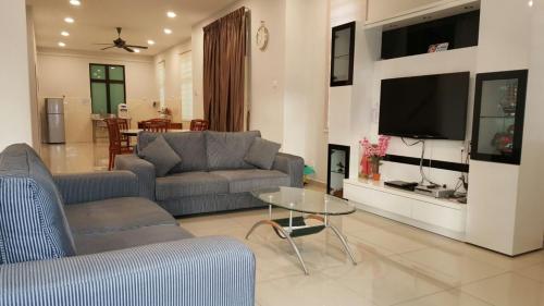 a living room with a couch and a table and a tv at Woon Homestay in Balik Pulau