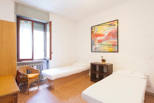 a room with two beds and a chair and a window at OstellOlinda in Milan