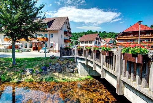 un pont sur une rivière dans une ville fleurie dans l'établissement Hotel Restaurant Schwörer, à Lenzkirch
