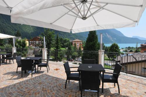 a patio with tables and chairs under a white umbrella at Alpenresort Belvedere Wellness & Beauty in Molveno