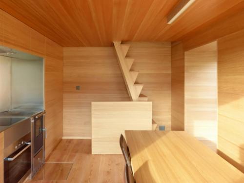 Habitación con paredes de madera, mesa de madera y escaleras. en Chalet Le Biolley, en Orsières