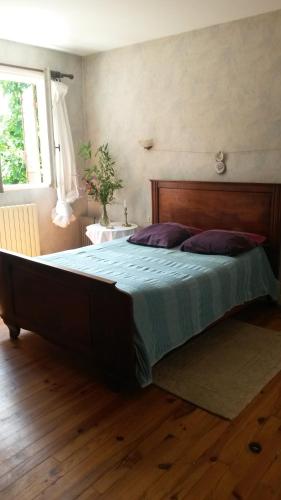 een slaapkamer met een groot bed met een houten hoofdeinde bij l'estanquet in Eauze