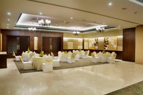 a banquet hall with white tables and white chairs at Goldfinch Hotel Delhi NCR in Faridabad
