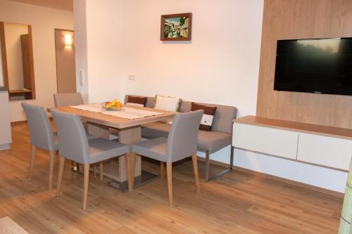 a dining room with a table and chairs and a flat screen tv at Stallerhof in Sankt Jakob in Haus