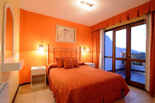 a bedroom with orange walls and a bed and a window at Terrazas de Merlo Aparts con servicios in Merlo