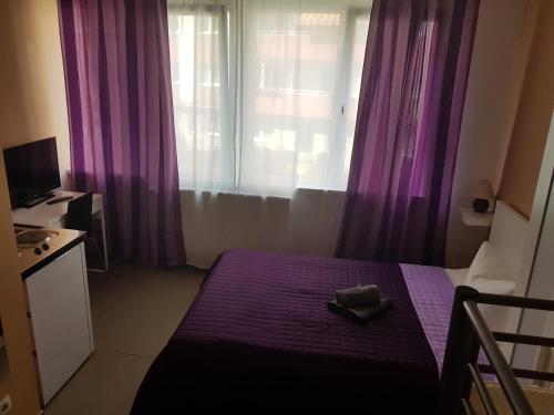 a bedroom with purple curtains and a bed with a hat on it at Elifim in Berlin