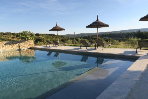 a group of chairs and umbrellas next to a swimming pool at Le Clos d'Estellan - Piscine chauffée in Bonnieux