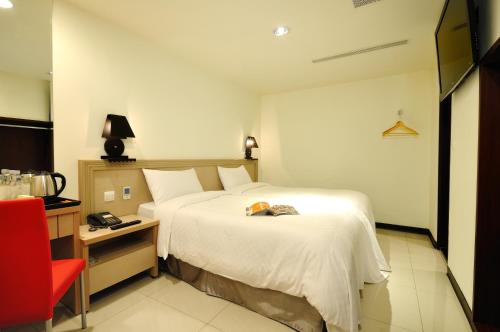ein Hotelzimmer mit einem großen Bett und einem roten Stuhl in der Unterkunft Bravo Hotel in Taichung