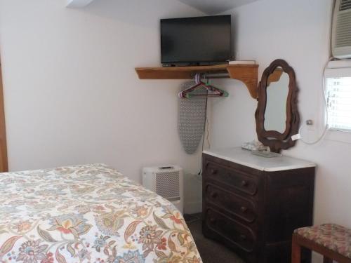 a bedroom with a bed and a tv and a dresser at Scarborough Inn in Manteo