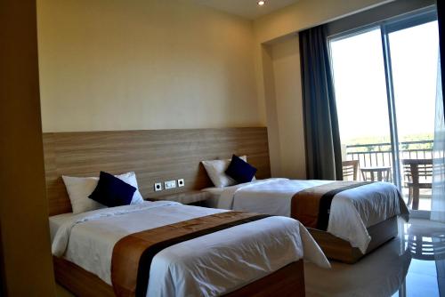Padadita Beach Hotel في وينغابو: سريرين في غرفة الفندق مع شرفة