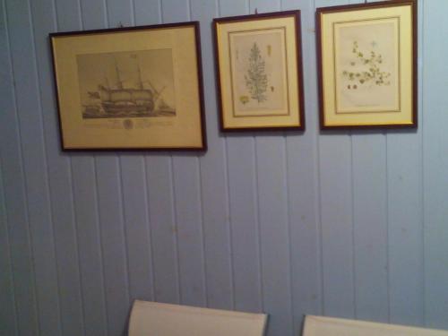 four pictures hanging on a wall above three toilets at The Merchant of Venice in Venice