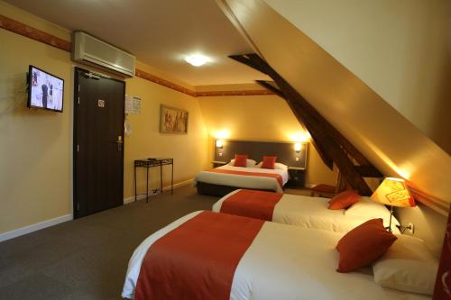 a hotel room with two beds and a flat screen tv at Hotel Henri IV in Coutras