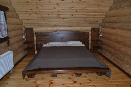 a bedroom with a bed in a wooden room at Gostynna sadyba Kit Bayun in Teterivka
