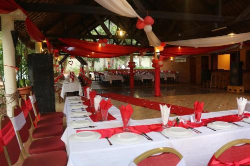 AR Sun Hotel في دييجو سواريز: صف طاولات بمناديل حمراء وكراسي حمراء