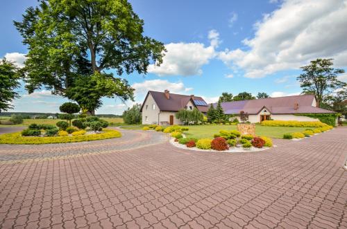 a brick driveway leading to a house with a garden at Zielona Przystań in Manasterz