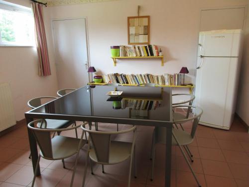 a dining room table with chairs and a refrigerator at La Closerie in Saint-Nizier-le-Bouchoux