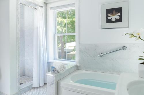 a white bathroom with a tub and a window at West Neck Guesthouse in Shelter Island Heights