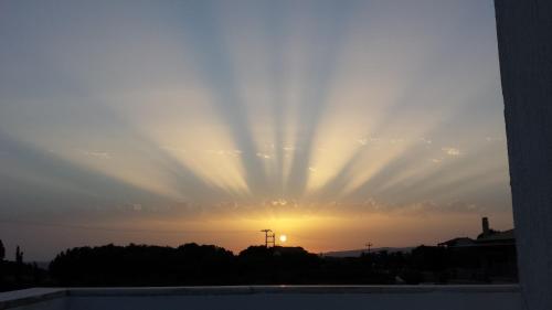 a sun setting in the sky with the sunrays at Eva Apartments in Svoronata