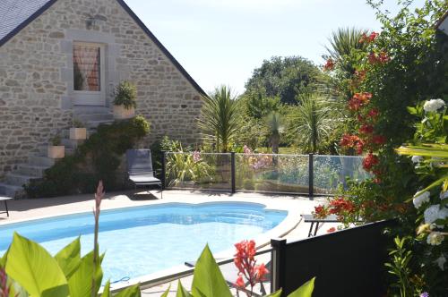 una piscina frente a una casa con flores en La Ferme de Kerraoul, en Combrit