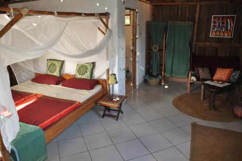 a bedroom with a canopy bed with red pillows at The Beach Crab Resort in Pangani