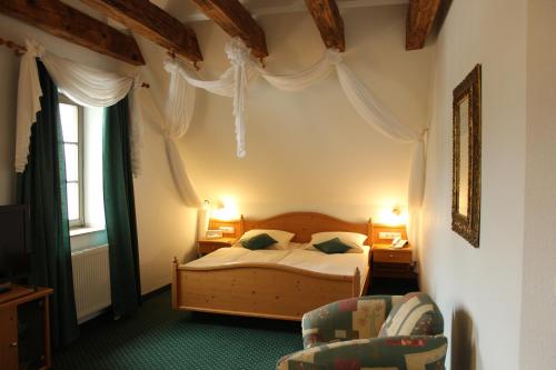 a bedroom with a bed and a chair at Hotel Lay-Haus in Limbach-Oberfrohna