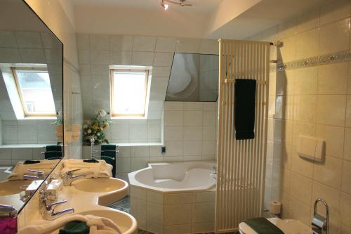a bathroom with two sinks and a bath tub at Hotel Lay-Haus in Limbach-Oberfrohna