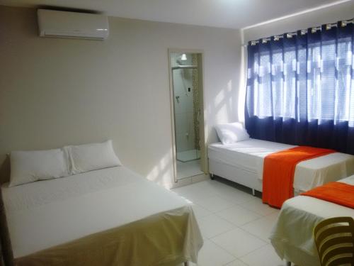 a small room with two beds and a window at Pousada Itararé in Campina Grande