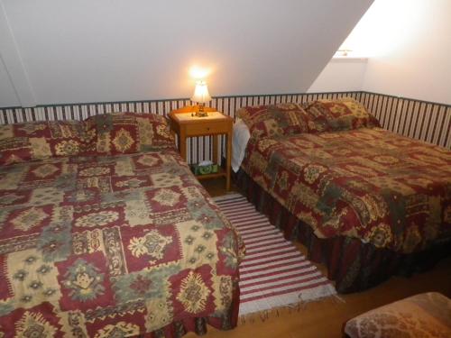 a bedroom with two beds and a table with a lamp at Auberge La Seigneurie Valcartier in Saint-Gabriel-De-Valcartier