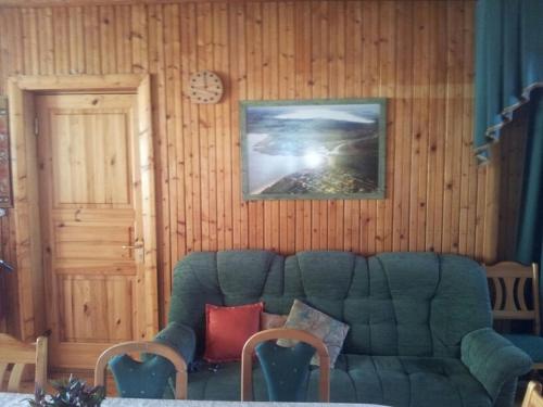 a living room with a green couch and a clock at Eha Suija Home Accommodation in Tartu