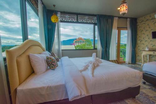 a bedroom with a large white bed in front of a window at Sridonchai Heritage, Night Bazaar Chiang Mai in Chiang Mai