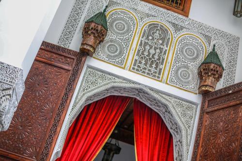 an ornate doorway with red curtains in a room at Palais Nazha Fes - Luxury Lodging in Fès