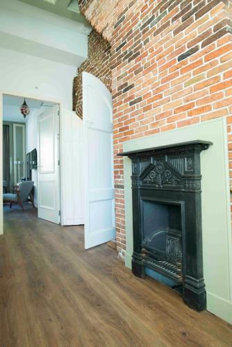 a living room with a fireplace and a brick wall at Logement 't Oude Bierhuys in Middelburg