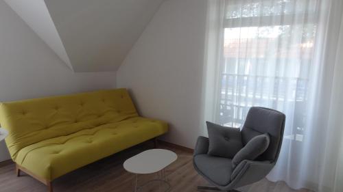 a living room with a yellow couch and a chair at Preila Holiday in Preila