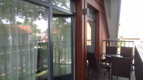 a screened porch with glass doors and a table and chairs at Preila Holiday in Preila