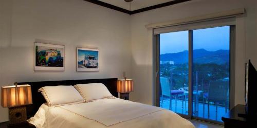 a bedroom with a bed and a large window at Best in Jaco Condos at Diamante del Sol in Jacó