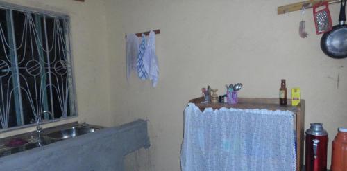 Rwenzori Trekking Homestay في Nyakalengija: مطبخ مع حوض وستارة زرقاء