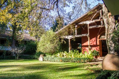 a red house with a garden in the yard at Hacienda los Lingues Chile Valle de Colchagua in Los Lingues