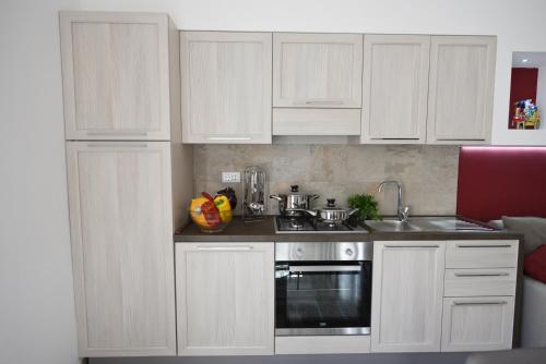 a white kitchen with white cabinets and a sink at Deliamare in Castellammare del Golfo