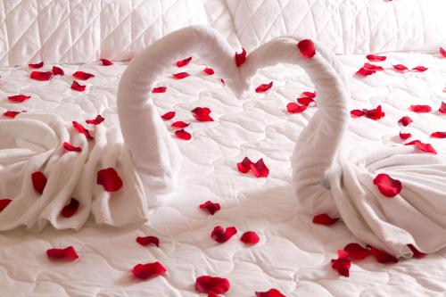 two white swans laying on a bed with hearts at Serema Palace Hotel in Lavras