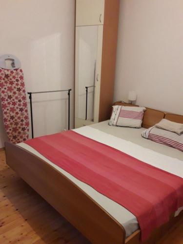 a bedroom with a bed with a red and white blanket at Apartment Hela in Zadar