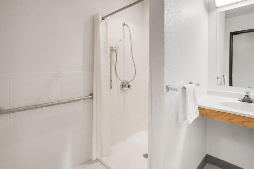 a white bathroom with a shower and a sink at Super 8 by Wyndham Grayling in Grayling