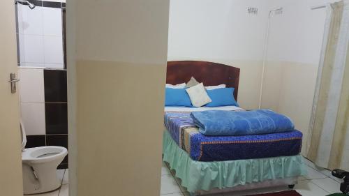 a bedroom with a bed with blue pillows and a toilet at The Palace Guest House in Harare
