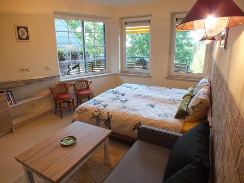 a bedroom with a bed and a table and windows at Apartments Ąžuolas in Palanga