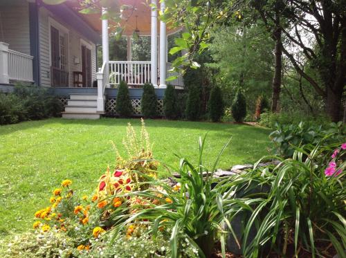 a yard with a house with a porch and flowers at Williston Village Inn in Burlington