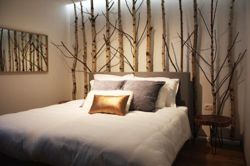 Un dormitorio con una cama blanca con árboles en la pared en Apartmaji 43, en Tolmin