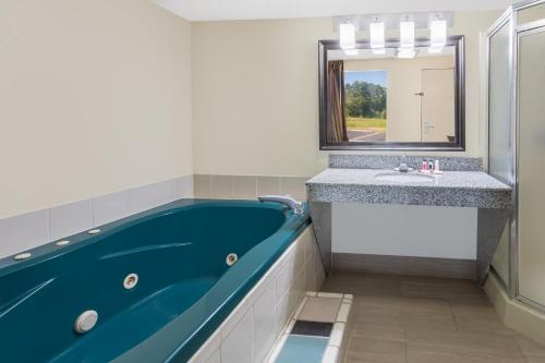 a bathroom with a blue tub and a sink at Days Inn by Wyndham Newberry South Carolina in Newberry
