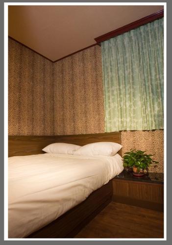 a bedroom with a bed with white sheets and a window at Hotel Lee-Chan in Taipei